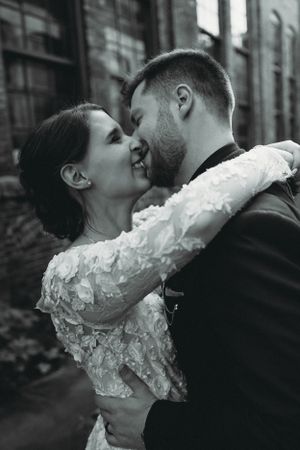 Intimate black and white close-up of couple sharing romantic moment by brick wall.