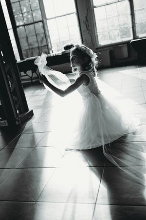 Silhouette of young dancer in flowing white dress against sunlit window.