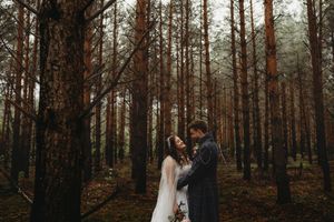 Romantic wedding couple shares intimate moment in misty pine forest.