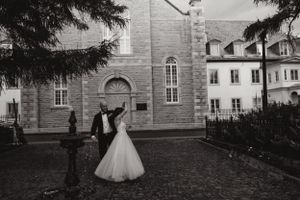 Elegant black and white wedding photo in front of a historic stone church building.