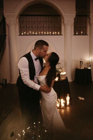Romantic dance between newlyweds with candlelit archways in the background.