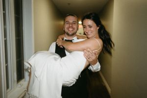 Traditional wedding carry pose in hotel hallway after ceremony.