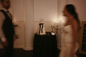 Wedding cake display on black tablecloth with candlelight creating a romantic atmosphere.