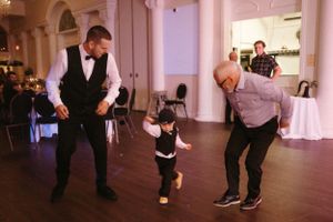 A young child dances with two adults on the dance floor at a wedding reception.