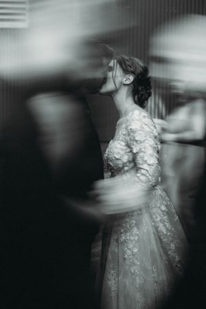 Artistic black and white photo of a bride in lace dress with motion blur effect.
