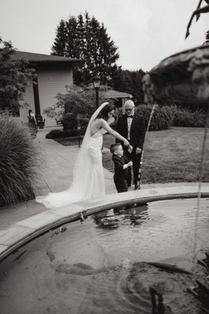A small group gathers around a pond in a backyard garden setting.