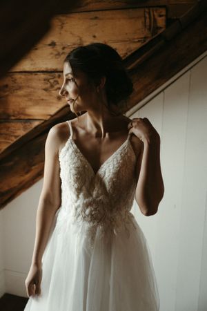 A wedding dress with delicate lace detail and tulle skirt in soft window lighting.