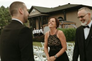 Wedding party members sharing laughter during an outdoor ceremony setup.