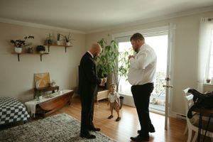 Two people in formal attire preparing for an event in a living room setting.