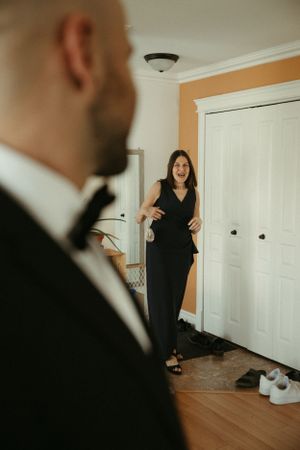 A glimpse of someone wearing a formal black dress standing near white doors as seen from over a person's shoulder.