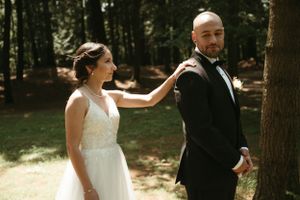 A wedding couple poses together in a sun-dappled forest setting, creating a romantic atmosphere.