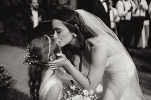 A tender moment during a wedding with a bride and flower girl in a white dress.