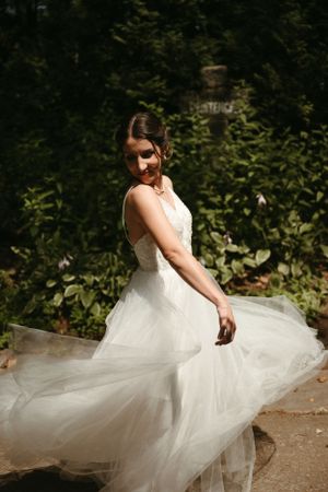 A bride twirls her flowing white dress in a dreamy forest setting.