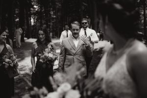 Photographie documentaire d'un mariage montrant des personnes marchant ensemble sur un chemin bordé d'arbres à l'extérieur.