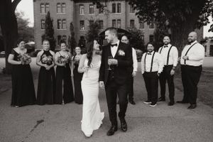 A black and white wedding photo with the wedding party posing outside a historic building.