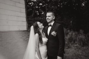 A romantic black and white portrait of newlyweds sharing an intimate moment outdoors.