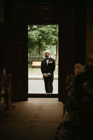 A silhouette of a groom waiting in a church doorway before the ceremony.