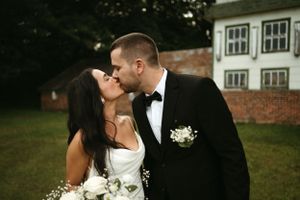 A tender moment between newlyweds with white flowers against a classic building backdrop.