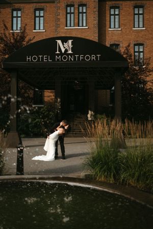 A dramatic wedding photo at Hotel Montfort entrance with ornate brick architecture.