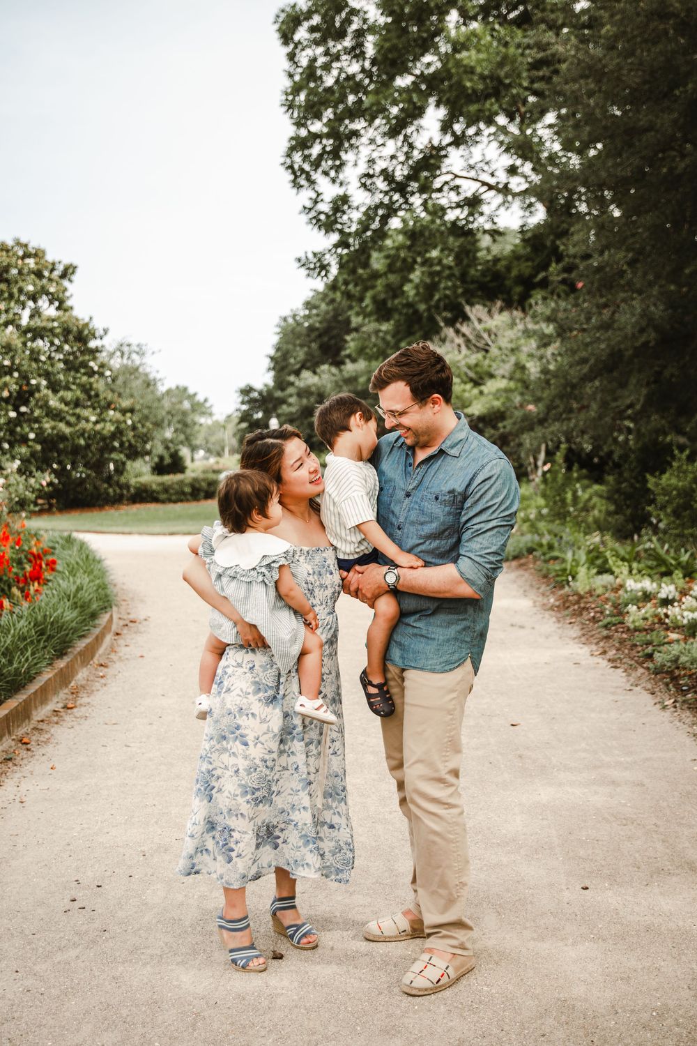 A tender family moment captured in a series of candid interactions on a garden pathway surrounded by greenery.