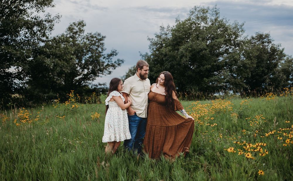 People in casual attire walk through a vibrant meadow filled with yellow wildflowers on a summer day.