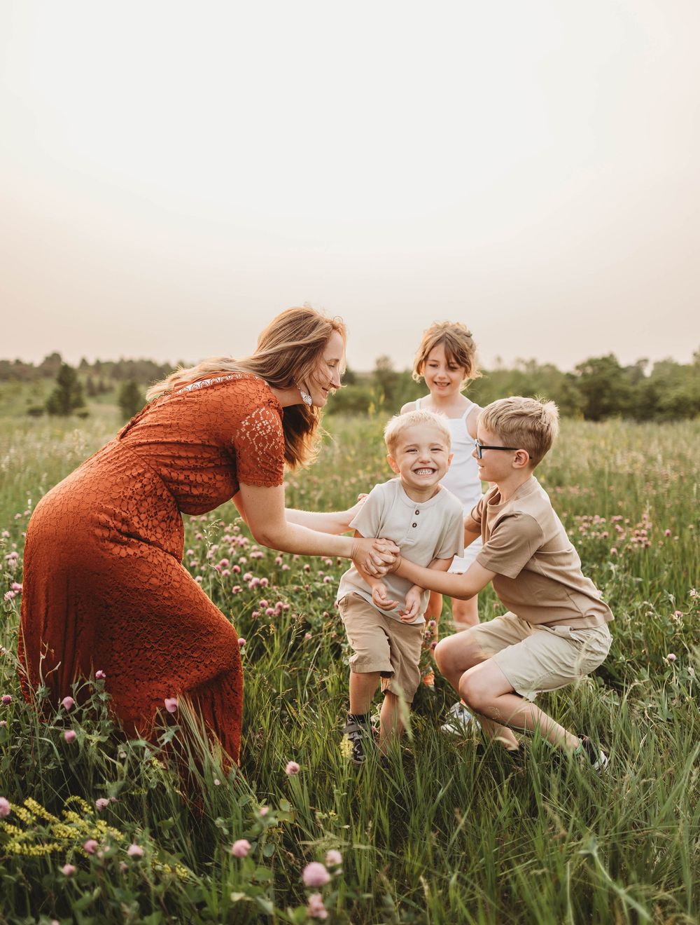 A group plays together in a serene meadow during golden hour, capturing joyful moments among wildflowers and tall grass.