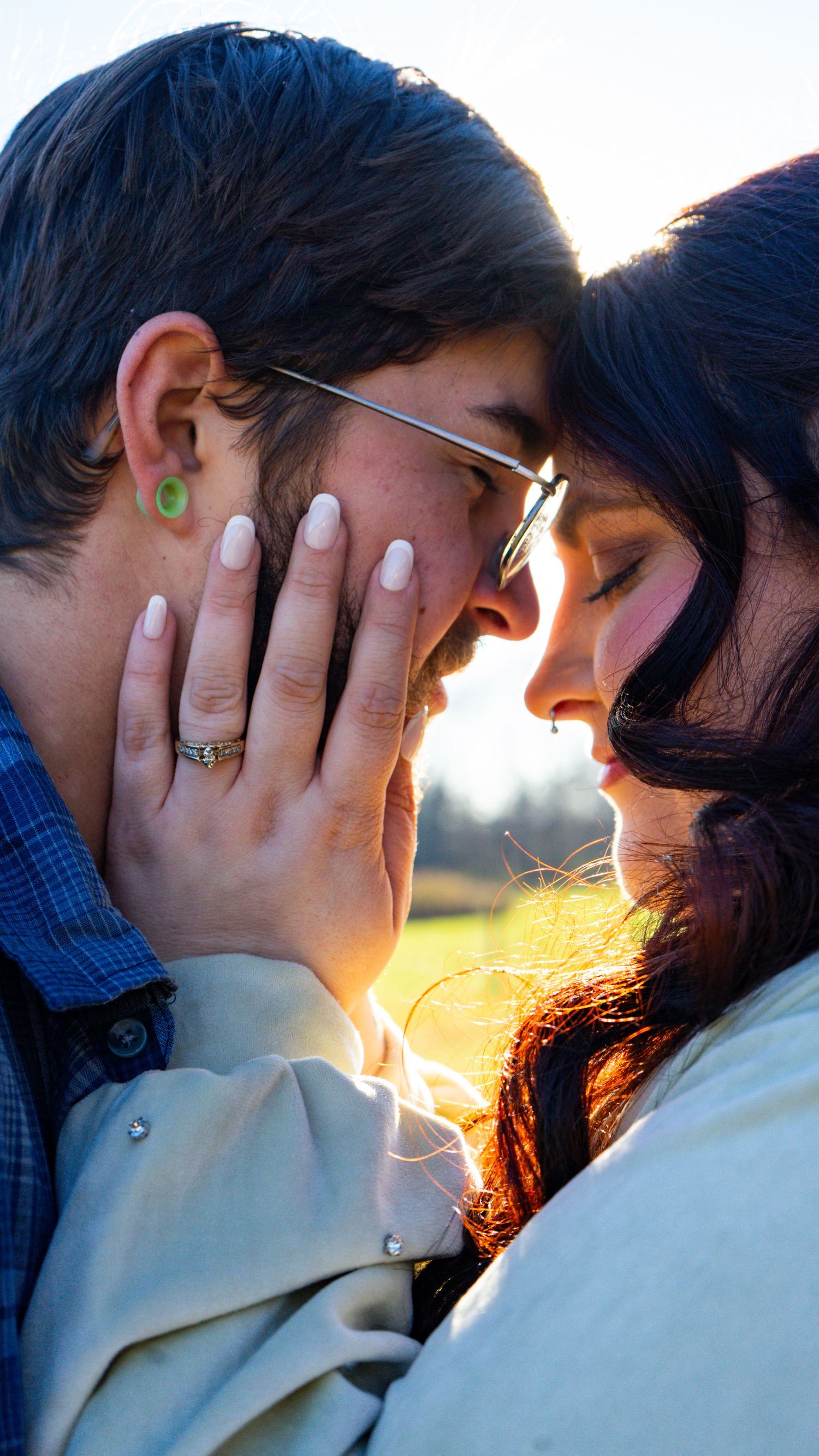 A tender romantic moment captured in sunlight showing two people's faces close together with a ring on display.