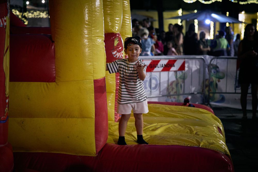 Young child playing on a yellow and red inflatable bounce house at a nighttime event.