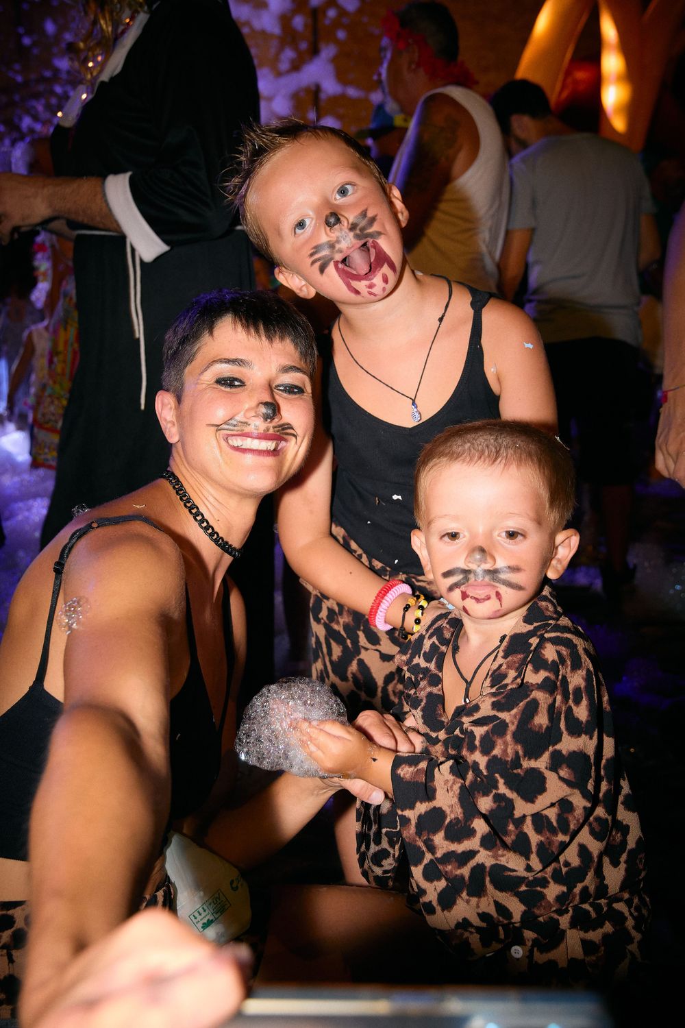 Three people with painted faces in costume posing together at a festive event.