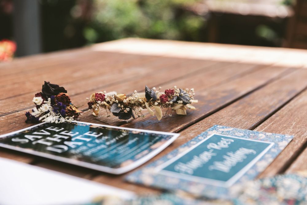 Wedding invitations and floral accessories arranged on wooden deck.
