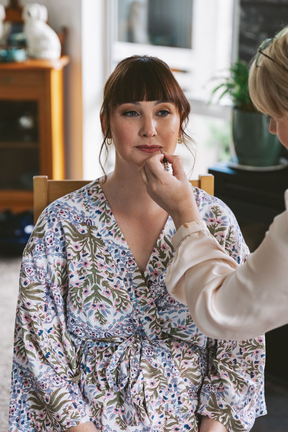 Makeup artist applying lipstick during bridal preparation.