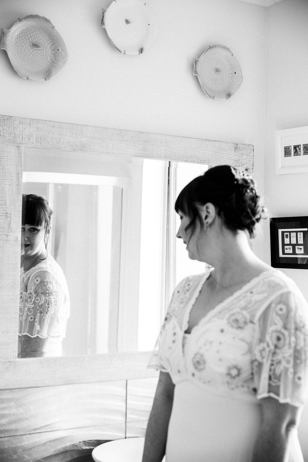 Black and white portrait of bride looking in mirror before ceremony.