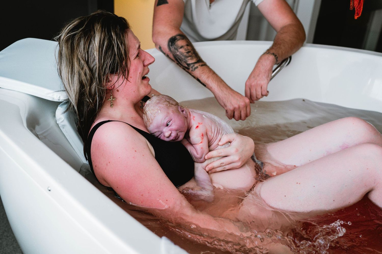 Water birth scene showing first moments with newborn in birthing tub.