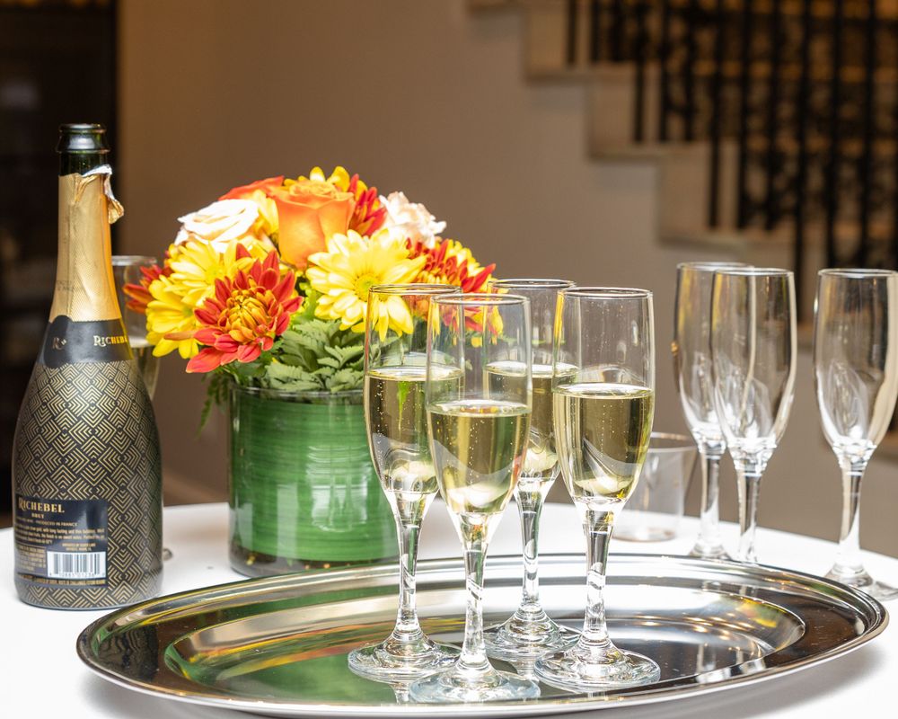Champagne glasses and vibrant orange and yellow flowers detail shoot during event photography in Weston, MA near Boston, Massachusetts.