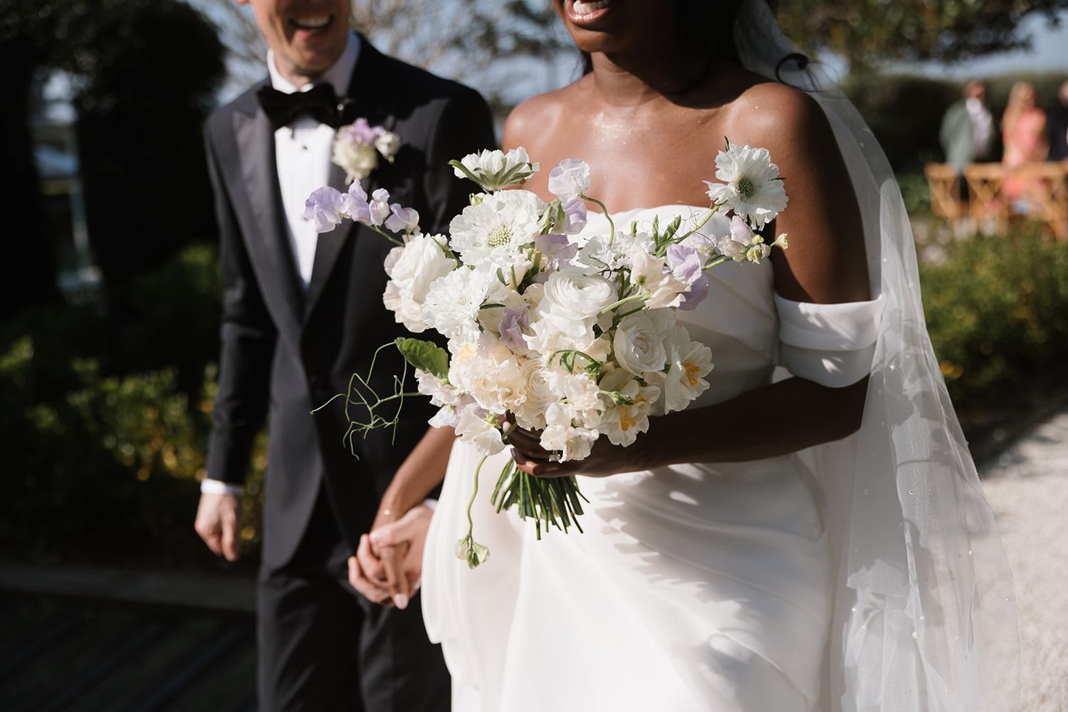 A couple on their wedding day with the bride holding an elegant white floral bouquet.