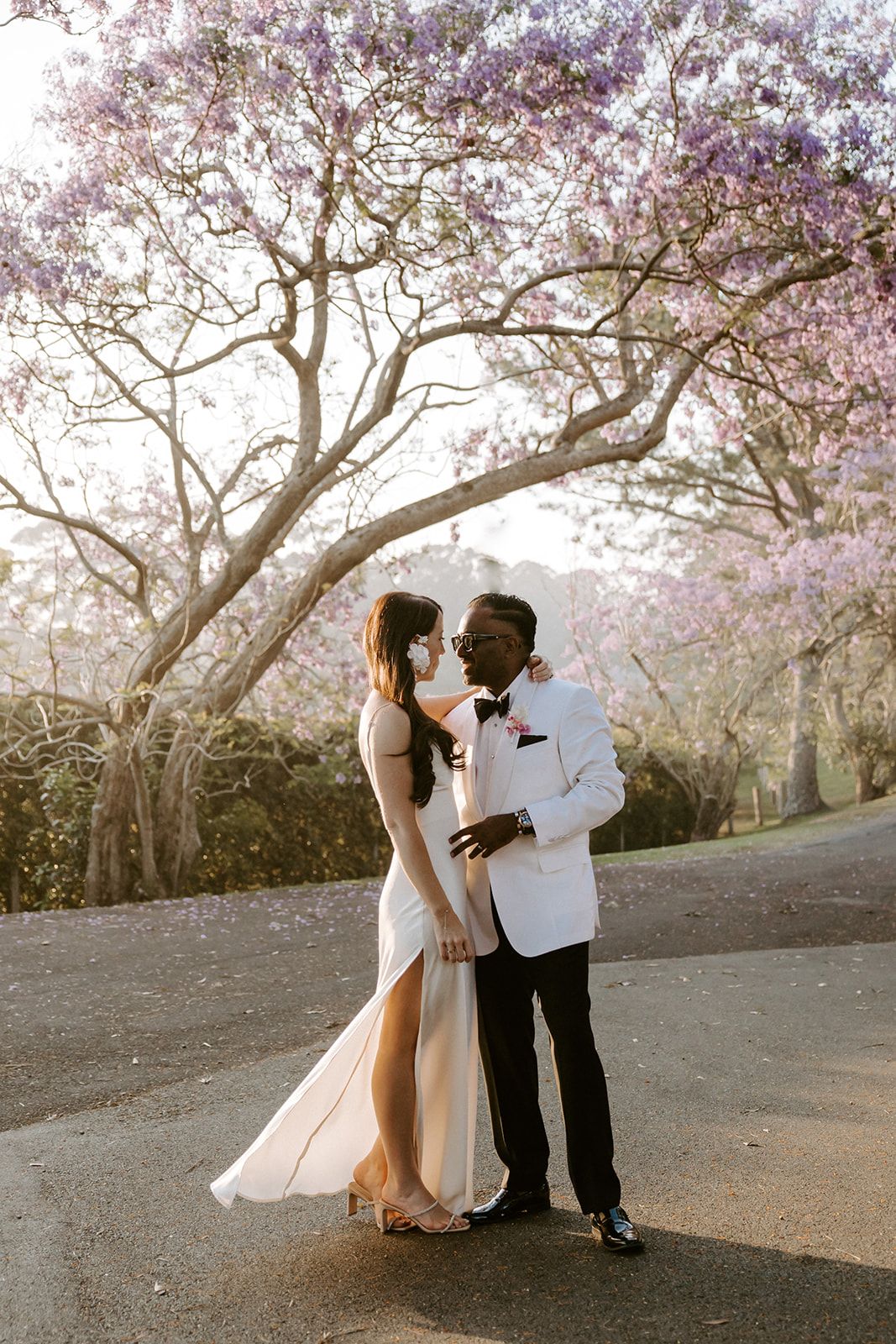 Romantic couple embracing under blooming cherry blossom trees at sunset.