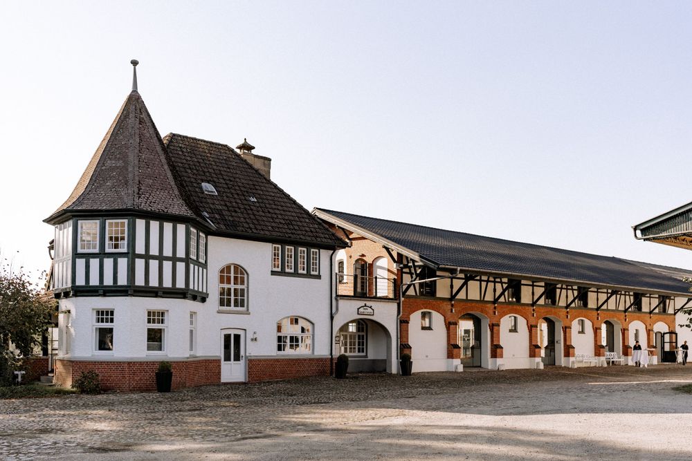 Historic Tudor-style building with white walls and timber framing featuring arched doorways.