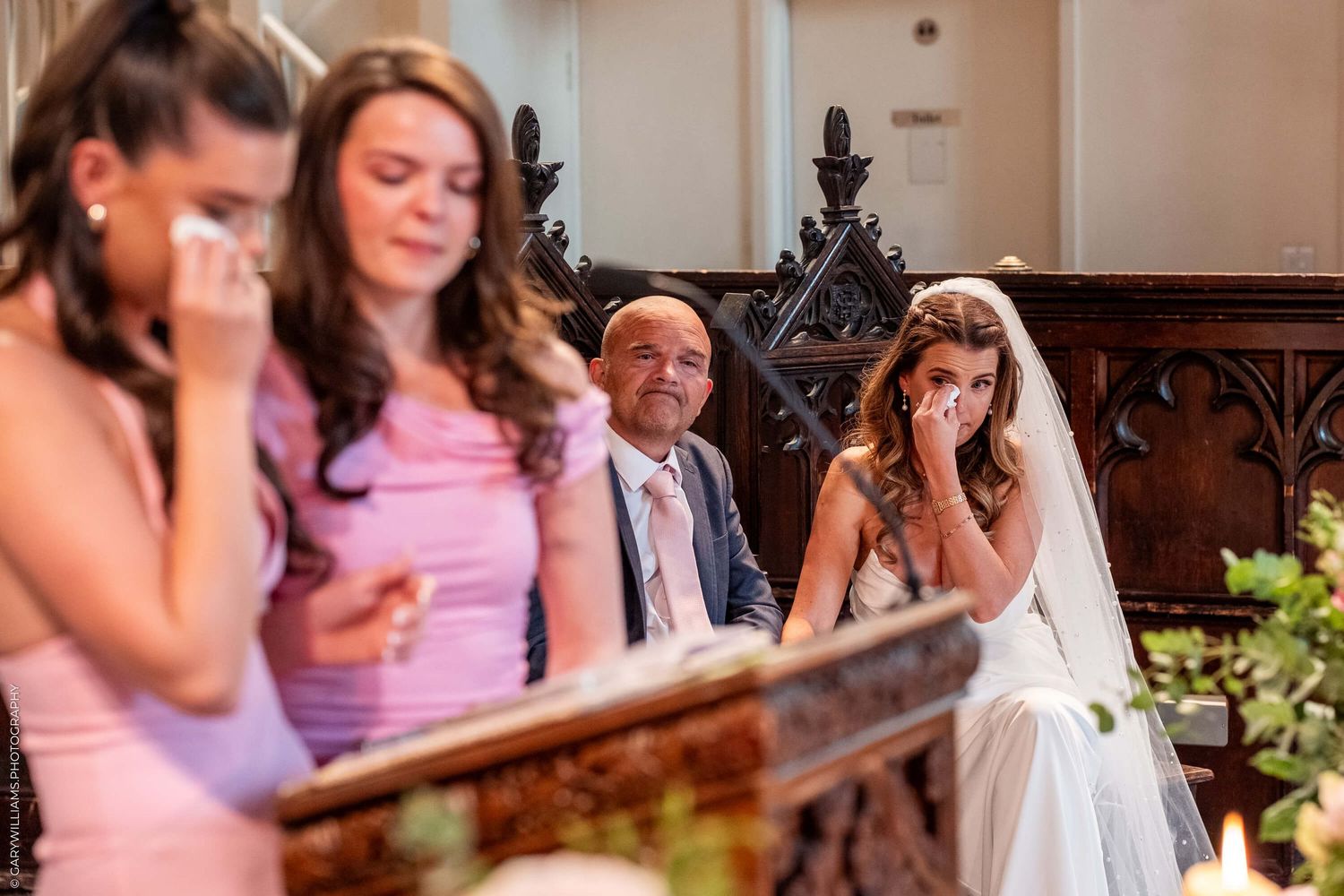A group shares an emotional moment during a church ceremony while seated on wooden pews.