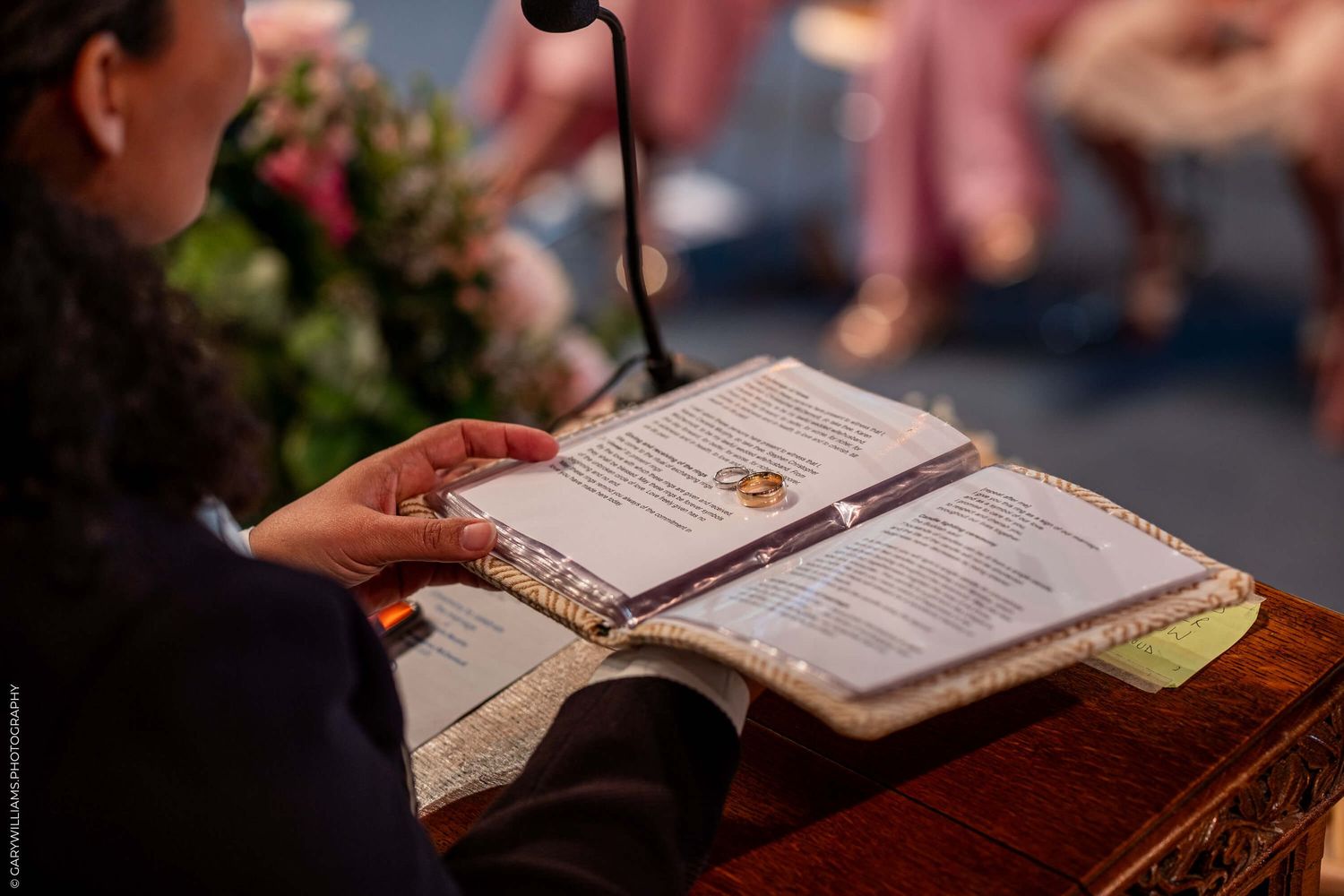 A person reads from an open book or menu on a wooden surface in soft lighting.