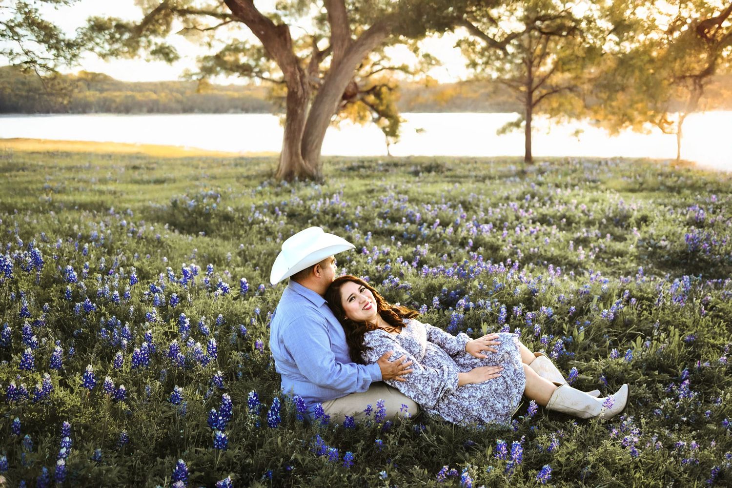 Romantic engagement moment captured beside the lake with wildflowers in full bloom on the Ennis Bluebonnet Trail