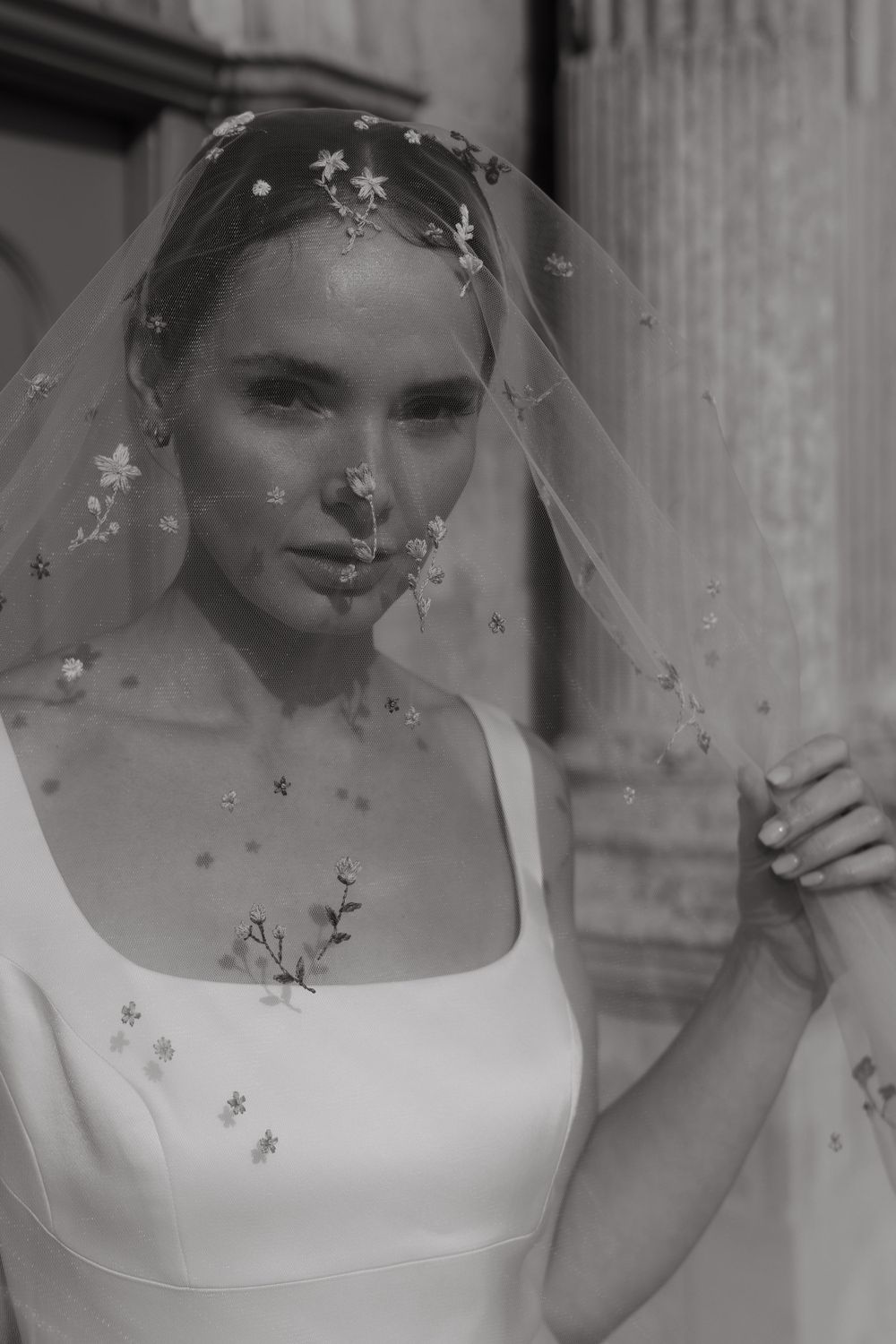 Black and white bridal portrait showing delicate floral veil details and classic simple wedding gown silhouette.