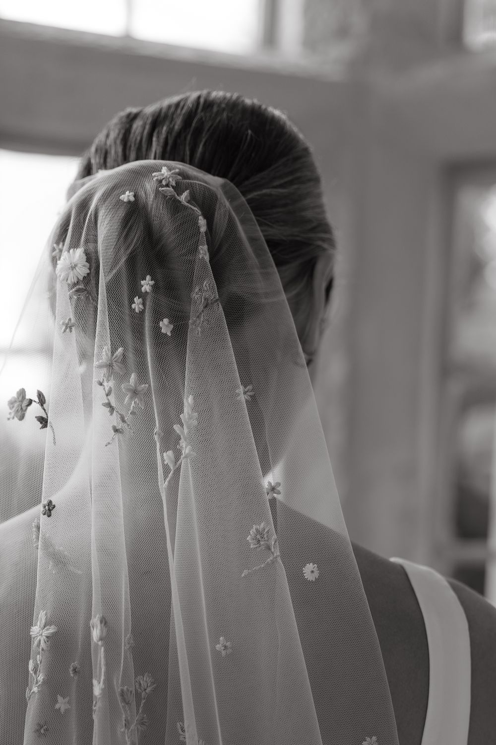 A back view of a bride wearing a delicate veil with small floral embellishments in black and white.