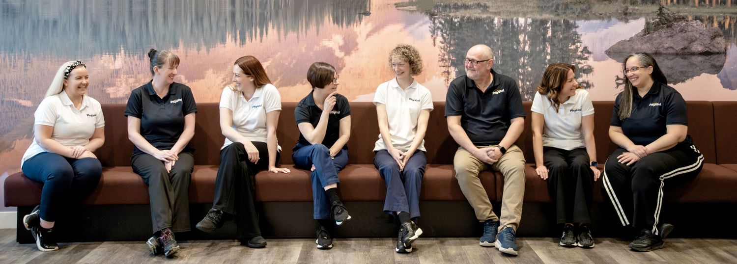 A group of young people sitting casually on a bench against a painted wall mural.