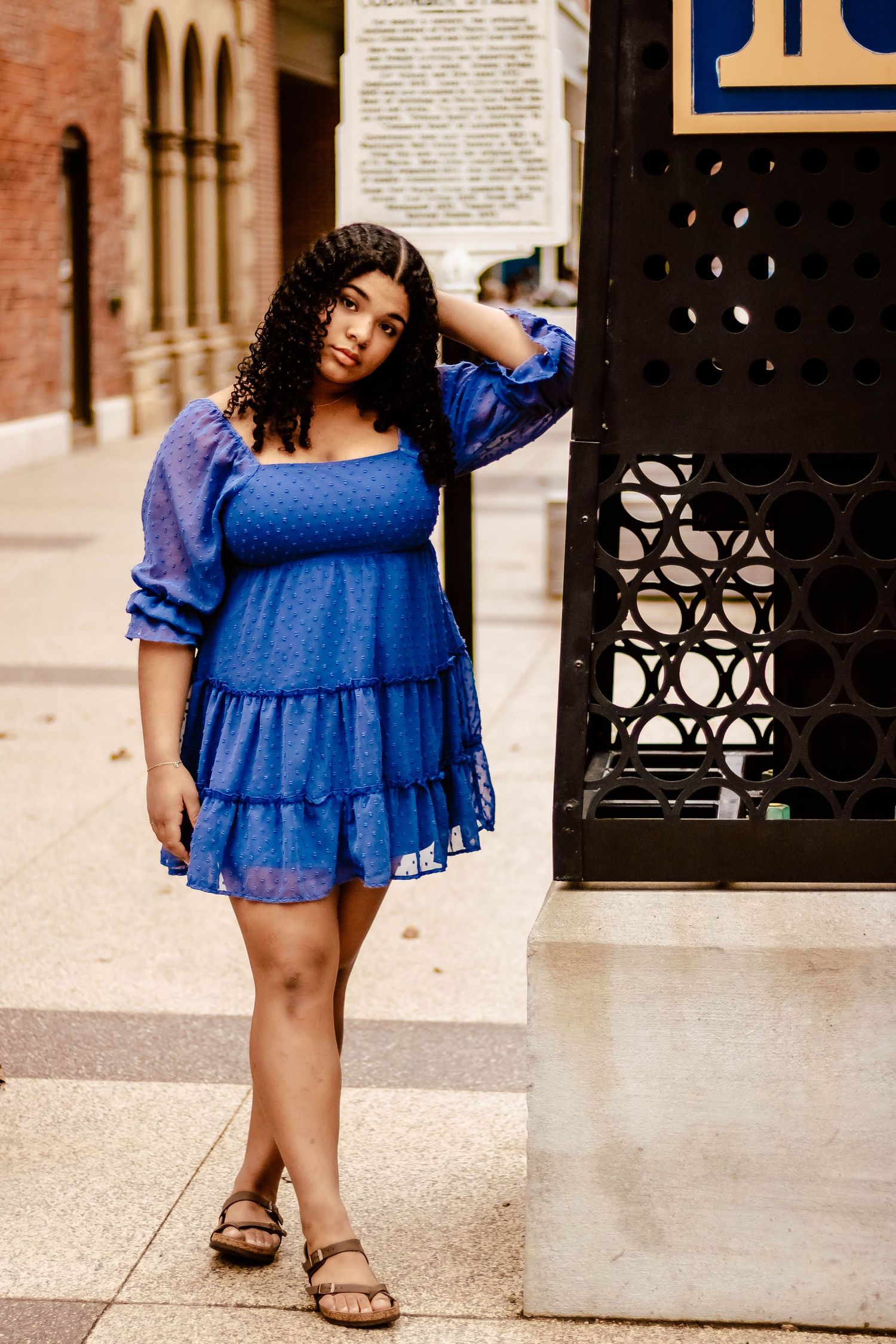 A vibrant blue tiered mini dress with puff sleeves styled with casual sandals in an urban setting.