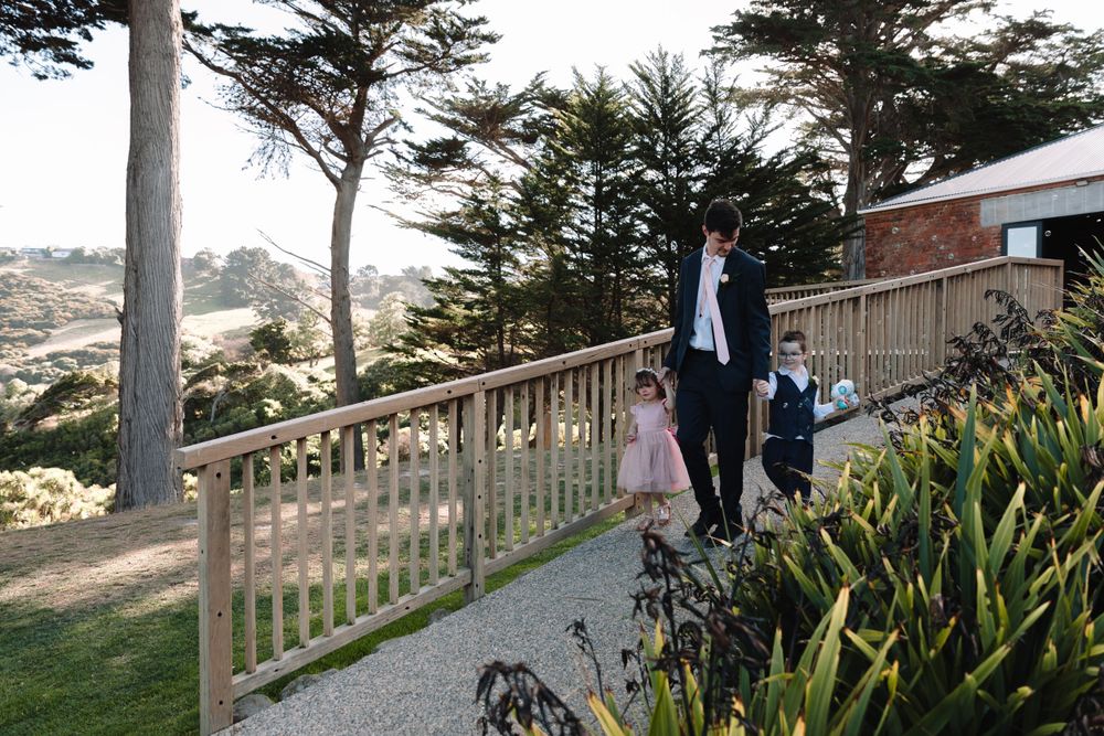 People walking along a coastal pathway with cypress trees and ocean views.