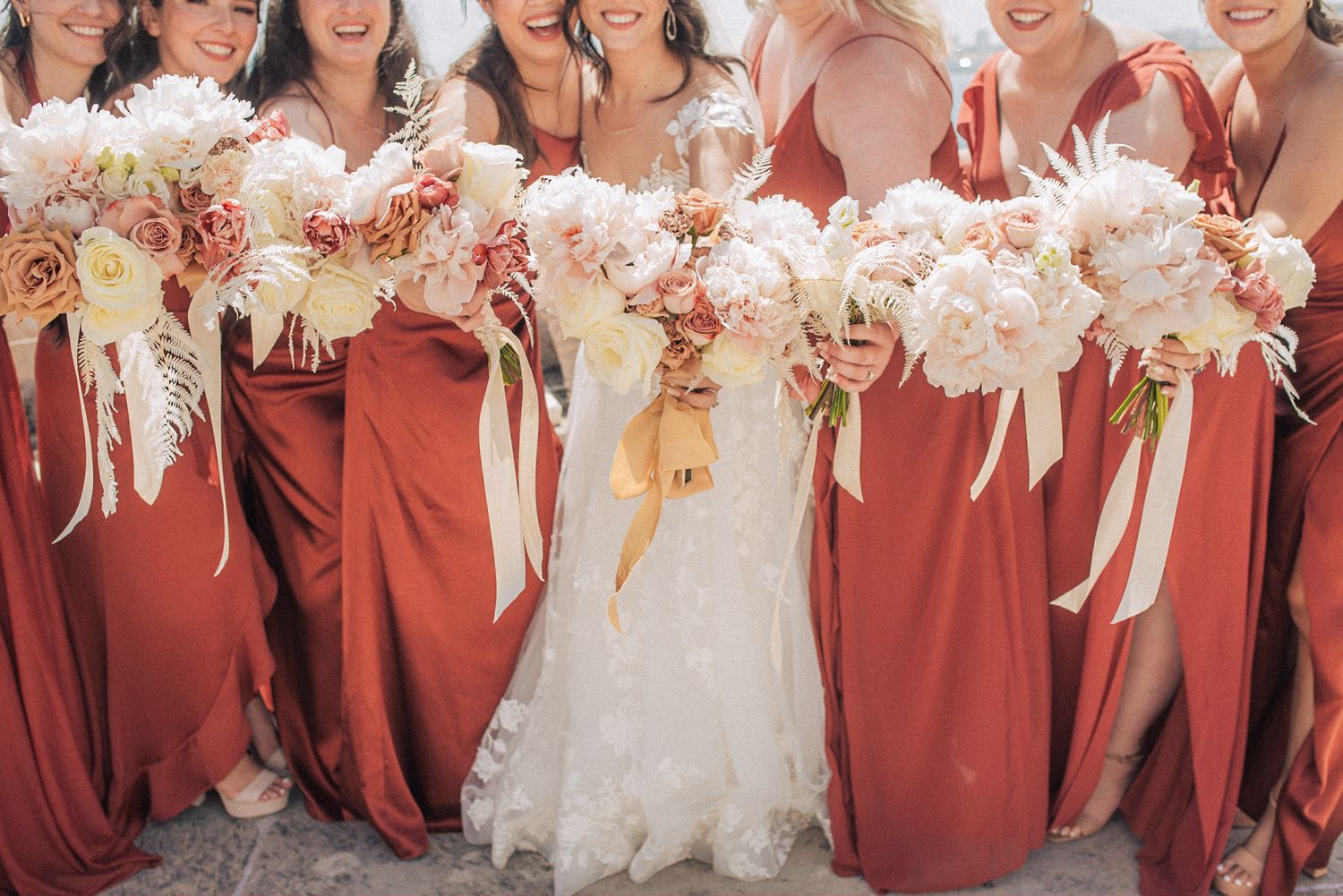 Wedding party holding luxurious white and blush bouquets at forte da Cruz. captured by a Lisbon destination wedding photographer