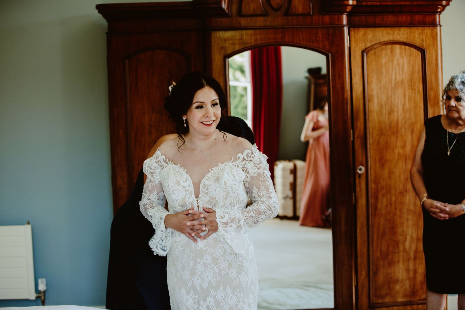 A bride in a lace wedding gown with long sleeves is captured in a series of elegant getting-ready photos.