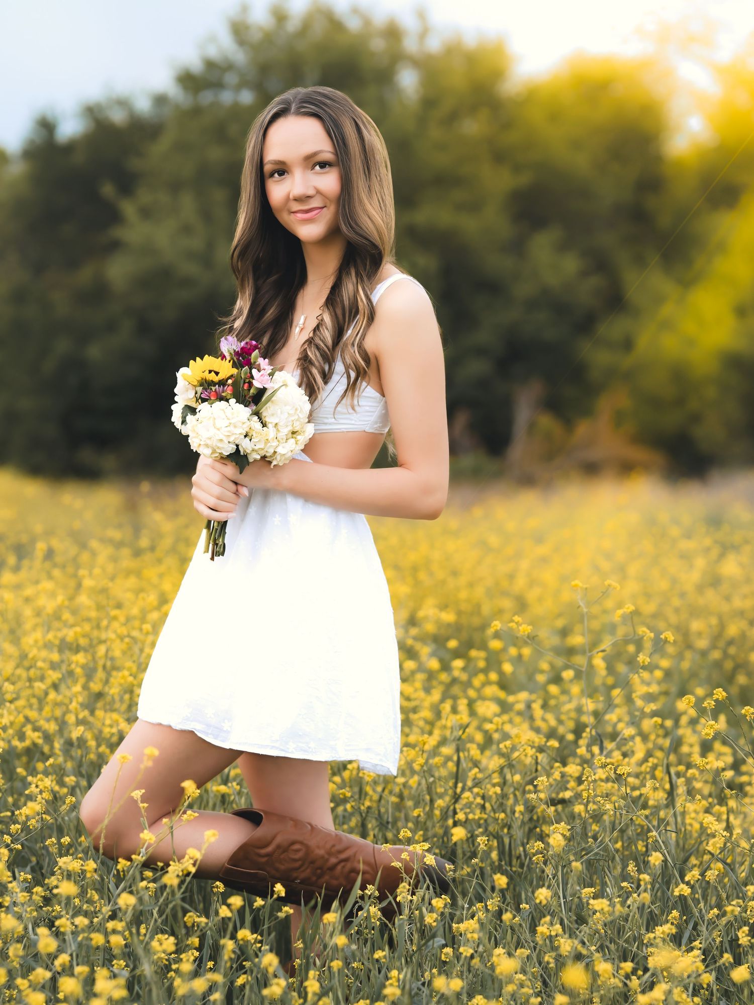 A white sundress-clad figure kneels in a vibrant field of yellow wildflowers while holding a spring bouquet at sunset.