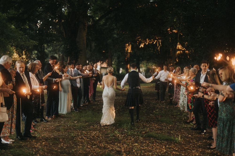 Evening wedding celebration with guests holding sparklers forming an illuminated pathway at Washingborough Hall - by Grimsby photographers.