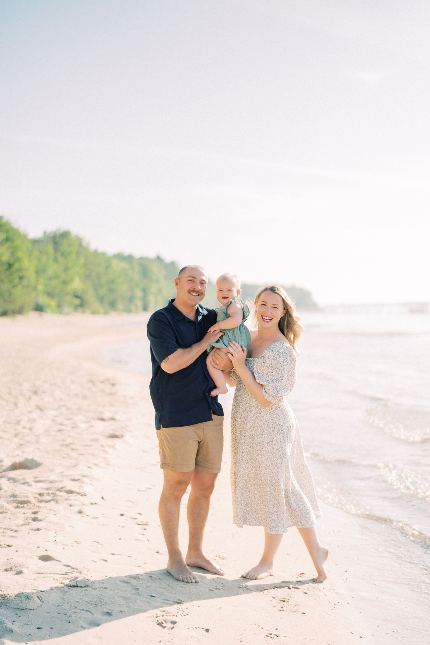 Two people share joyful moments together on a sunny beach with soft white sand and clear sky in the background.